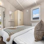 Schlafzimmer mit Bett, Kleiderschrank und Fenster. Durchgang zu Wohnbereich mit Kamin.