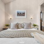 Schlafzimmer mit Bett, Wandbild und Pflanzen. Badezimmer im Hintergrund sichtbar.