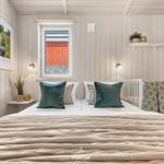 Schlafzimmer mit Bett, Krippe und Fenster mit Blick auf rote Wand.