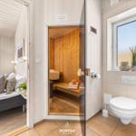 Schlafzimmer mit Sauna und Badezimmer. Holzwände, Fenster und Toilette sichtbar.