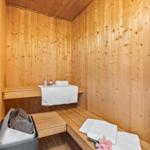 Sauna mit Holzwand, Bänken, Handtüchern und Blume