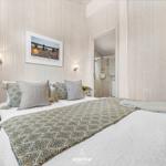 Schlafzimmer mit Bett, Wandbild und angrenzender Dusche.