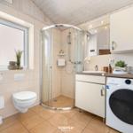 Badezimmer mit Dusche, Waschmaschine und Fenster.