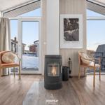 Raum mit Kamin, zwei Stühlen und Blick auf Schnee und Balkon.