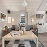 Wohnzimmer mit Sofa, Tisch und Stuhl. Holzwände und Decke. Fenster mit Vorhang.
