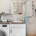Badezimmer mit Dusche, Waschmaschine und Spiegel