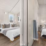 Zwei Schlafzimmer mit Betten, Holzwänden und Fenstern. Ein Raum hat eine Wiege.