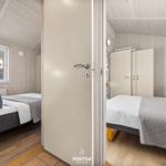 Zwei Schlafzimmer mit Betten, Kleiderschränken und Fenstern. Holzwände und Boden.