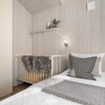 Schlafzimmer mit Bett, Kinderbett und Kleiderschrank. Holzwände und Fenster.