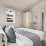 Schlafzimmer mit Bett, Kleiderschrank und Fenster. Blick auf Außenbereich.
