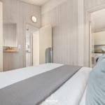 Schlafzimmer mit Bett, Kleiderschrank und Blick in die Küche.