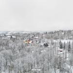 Schneebedeckte Landschaft mit Häusern und Wäldern in einer Bergregion.