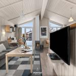 Wohnzimmer mit Sofa, Couchtisch, Kamin und Fernseher an Wand.