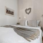 Schlafzimmer mit Bett, Holzwand und Bild an der Wand.