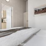 Schlafzimmer mit Bett, Wandbild und Blick in die Küche.