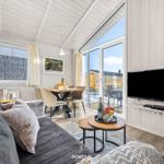 Wohn- und Essbereich mit TV, Tisch, Stühlen und Blick auf Balkon.