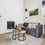 Wohnzimmer mit Sofa, Kamin und Fernseher. Holztische und Wandbild.