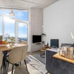 Wohn- und Essbereich mit großem Fenster, Sofa und Fernseher.