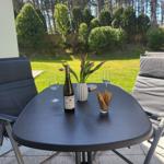 Außenbereich mit Tisch, zwei Stühlen, Wein, Tulpen und Gebäck.