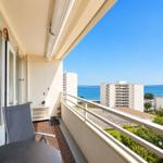 Balcony with seating and view of the sea and high-rise buildings.