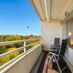 Balcony with table and chairs, view of forest and tower.