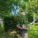 Garten mit Grill, Spielplatz und Sitzgelegenheiten unter Bäumen.