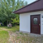 Haus mit brauner Tür und Steinweg im Garten mit Tisch und Stühlen.