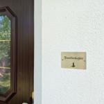 Schild an der Wand neben der Tür zeigt Familienkajüte mit Leuchtturm-Symbol.