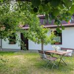Haus mit Garten, Tisch und Stühlen unter Bäumen. Fenster mit Blumenkästen.