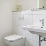 Bathroom with toilet, sink, and mirror. Window provides natural light.