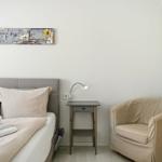 Bedroom with bed, armchair, and nightstand. Wall art above the bed.