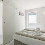 Bedroom with bed, window, and sliding door. Towel on bed.