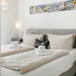 A bed with bedding, pillows, and towels. A painting hangs on the wall.
