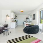 Apartment with sofa, dining area, and balcony. White walls and floor. Large bean bag.