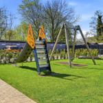 Childrens playground with slide and swing on green lawn.