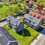 Modern apartment building with solar panels and garden. View of residential area with sports field.