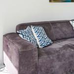 A gray sofa with blue cushions and white stitching against the wall.