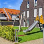 Backyard with playground, slide, and swing in front of brick house.