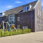 Modern multi-family house with playground and paved forecourt.