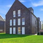 Modern brick house with green lawn and white window shutters.