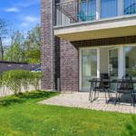 Terrace with table and chairs in front of a building with balcony and glass doors.