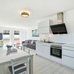 Kitchen with dining area, living room and TV. White built-in kitchen with stainless steel appliances.