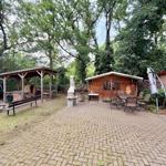 Holzhütte mit Sitzgelegenheiten und Grillbereich im Garten.