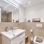 Badezimmer mit Waschbecken, Spiegel, Toilette und Dusche