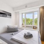 Schlafzimmer mit Bett, Fenster und Wandbild. Vorhang und Spielcontroller sind sichtbar.