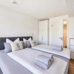 Schlafzimmer mit Doppelbett, Kissen, Handtüchern, Kleiderschrank und Nachttisch.