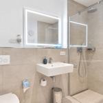 Badezimmer mit Dusche, Waschbecken und Spiegel