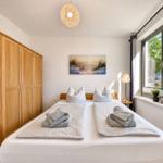 Bedroom with double bed, wooden wardrobe, and window view.