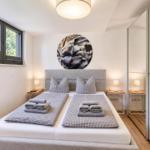 Schlafzimmer mit Doppelbett, zwei Nachttischen und Fenster mit Blick auf Bäume.