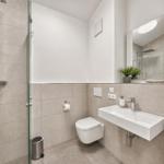 Moderne Dusche mit Glaswand, WC und Waschbecken mit Spiegel.